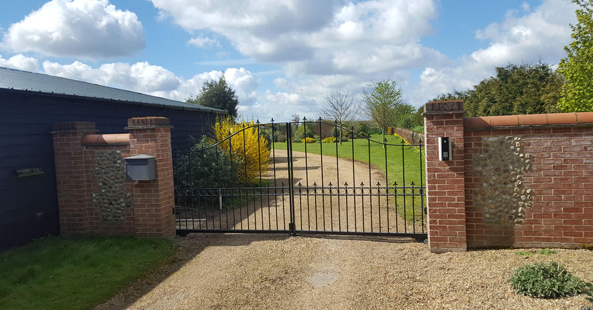 An automated steel gate on a gravel driveway